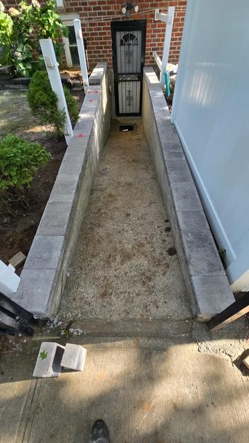 Basement entrance walkway before the concrete slab, with capped walls and a dirt base