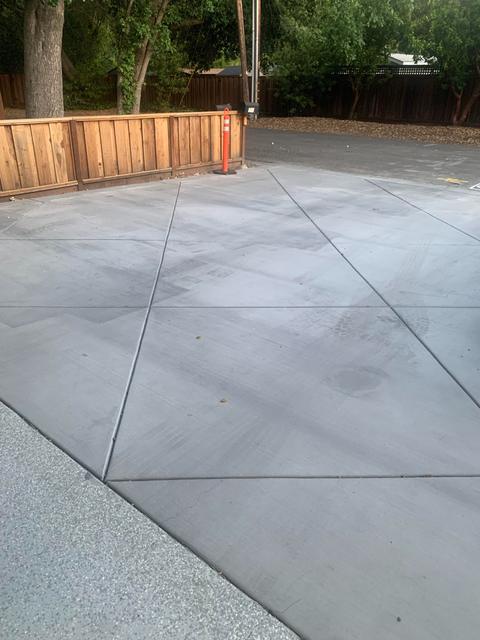 Broom-finished concrete patio with crisp control joints in front of a wood fence