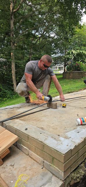 Mason fitting and cutting a cap on a segmental block retaining wall