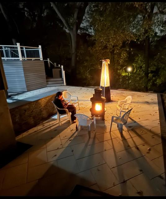 Backyard porcelain patio at night with a lit fire feature, patio heater and family seating